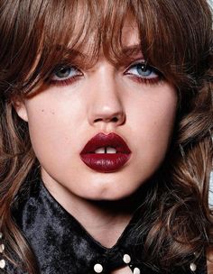 a close up of a woman with long hair and red lipstick on her face, wearing a black collar