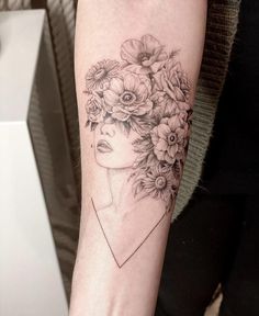 a woman's arm with flowers and a face tattoo on the left inner arm