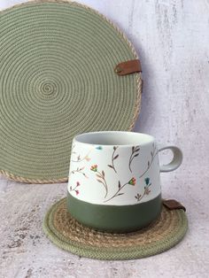 a green and white cup sitting on top of a place mat next to a basket