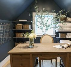 a desk with some flowers in a vase on top of it next to stacks of folded towels