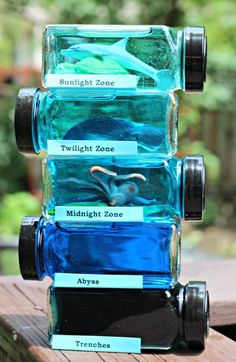 four empty water bottles sitting on top of a wooden table with labels in each bottle