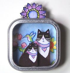 two cats sitting on top of each other in front of a bird and flower decoration