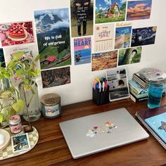 a laptop computer sitting on top of a wooden desk covered in pictures and magnets