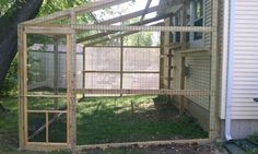 a chicken coop built into the side of a house next to a tree and grass covered yard