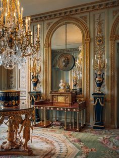 an elaborately decorated room with chandelier and table in front of large mirror