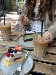 a woman sitting at a table with two plates of food and drinks in front of her