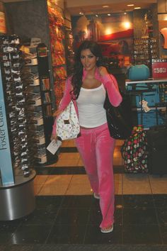 a woman in pink pants and white top walking through a store with her hand on her hip