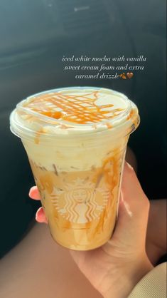 a person holding up a cup with orange liquid in it and the words, iced white coffee with vanilla sweet cream frozen and caramel flavor