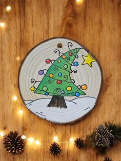 a wooden plaque with a christmas tree painted on it, surrounded by pine cones and lights