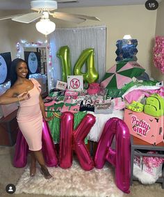 a woman standing in front of a table filled with balloons and presents for her birthday