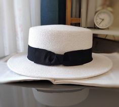 Stride under the sun with confidence! Our Boater Hat is not only stylish but provides a substantial shield from the harsh sun rays, boasting a UPF 50+ rating. The wide brim casts a comforting shade over your face, letting you revel in every outdoor soiree, beach outing, or casual day out in the city, without a worry. White Boater Hat With Flat Crown For Summer, Chic White Straw Boater Hat, Elegant Boater Hat With Flat Crown For Beach, Elegant Boater Hat With Flat Crown For Vacation, Outdoor Soiree, Straw Boater Hat, Leather Beret, Beach Outing, Straw Boater