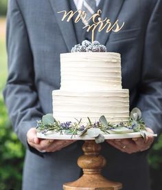 a close up of a person holding a cake on a wooden platter with the word mr and mrs written on it