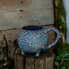 a blue vase sitting on top of a wooden stump