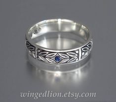 a wedding ring with an intricate design on it's side, sitting on a gray surface