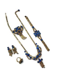 ** Blue Rhinestone Jewelry Set, Vintage 1960s Grand Parure, Faux Sapphire Necklace Brooch Bracelet Ring and Earrings, Costume Jewelry at Bat City Vintage ** Utterly breathtaking jewelry set from the 1960s. This set is a grand parure, including a necklace, a bracelet, a pair of earrings, a brooch, and a cocktail ring. Each piece is made of gold-tone metal set with round cut clear and dark blue rhinestones (faux sapphires.) The necklace, brooch, and earrings feature trailing strands of rhinestones Rhinestone Jewelry Set, Vintage Jewelry Sets, Enamel Necklaces, Bracelet Ring, Brighton Jewelry, Jade Bracelet, Sapphire Necklace, Rhinestone Jewelry, Enamel Jewelry