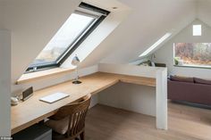 a room with a desk, couch and window in it's roof dormer