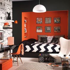 a bedroom with an orange wall, black and white bedding and pictures on the walls