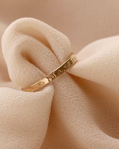 a gold wedding band sitting on top of a white cloth