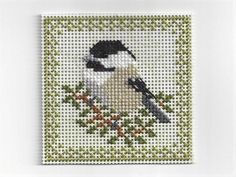 a cross stitch picture of a bird on a branch