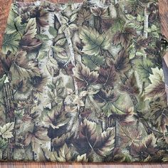 a wooden table topped with a green and brown blanket covered in leafy leaves next to a knife