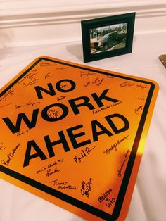 a no work ahead sign sitting on top of a white bed next to a framed photo