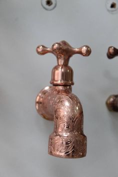 a copper faucet hanging from the side of a wall