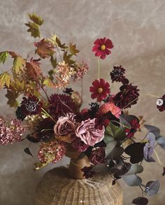 a vase filled with lots of flowers sitting on top of a wooden table next to a wall