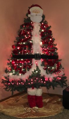 a decorated christmas tree with santa clause on it's top and red stockings underneath