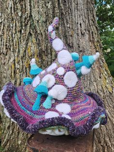 a knitted hat hanging from the side of a tree in front of a trunk