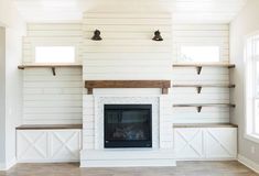 an empty living room with white walls and open shelvings on the wall, along with a fireplace