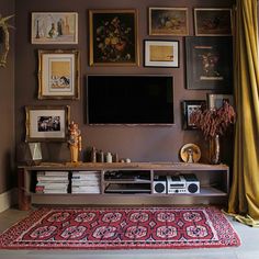 a living room with pictures on the wall and a rug in front of the tv