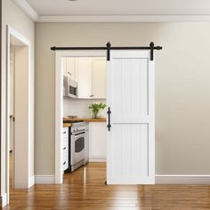 an open white door in a kitchen next to a stove top oven and microwave on a hard wood floor