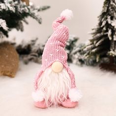 a small stuffed animal wearing a knitted hat and pink slippers in the snow