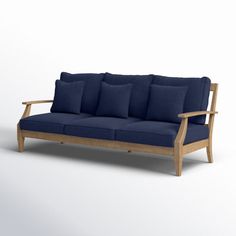 a wooden couch with blue cushions and pillows on it's back end, in front of a white background