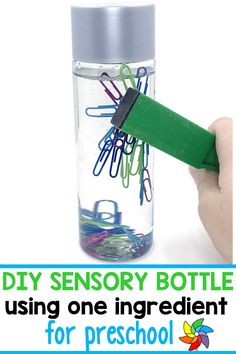 a hand holding a green marker over a bottle filled with paper clips