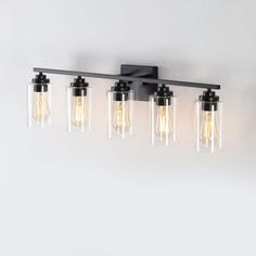 four light bathroom fixture with clear glass shades and black metal frame, on a white wall