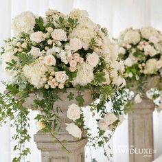 two vases with white flowers and greenery on the top one is filled with roses