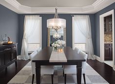 a dining room with blue walls and white curtains