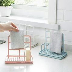 a person is holding two towels in front of a sink with a soap dispenser