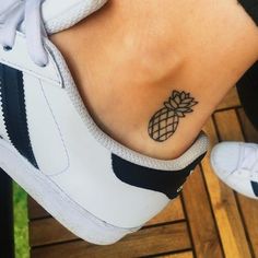 a pineapple tattoo on the foot of a woman's left foot, which is black and white