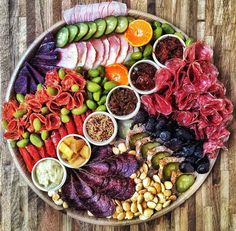 a platter filled with different types of meats and vegetables on top of a wooden table