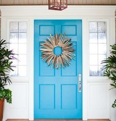 a blue front door with a wreath on it and potted plants next to it