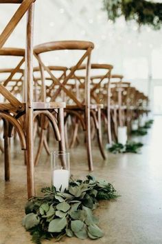 a candle is sitting on the floor in front of rows of chairs with greenery