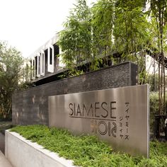 the sign for siame group in front of some trees and bushes on a sidewalk