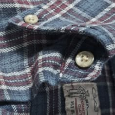 a close up view of a plaid shirt with buttons on the collar and chest pocket