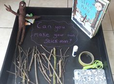 a tray with sticks, scissors and writing on it that says can you make your own stick man?