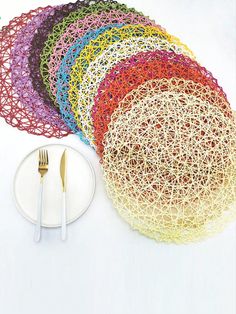 there are many pieces of crocheted paper on the table with forks and spoons