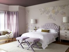 a white bed sitting in a bedroom next to a window with purple drapes on it