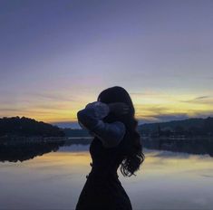 a woman holding a stuffed animal in front of a body of water