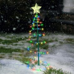 a small christmas tree with lights in the snow